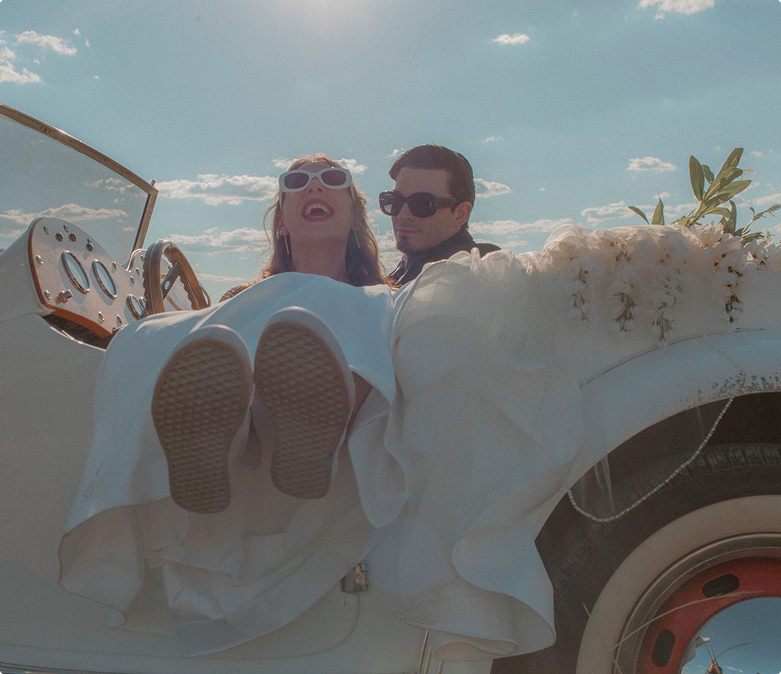 Bridge and groom in car with white flowers laughing on a sunny day