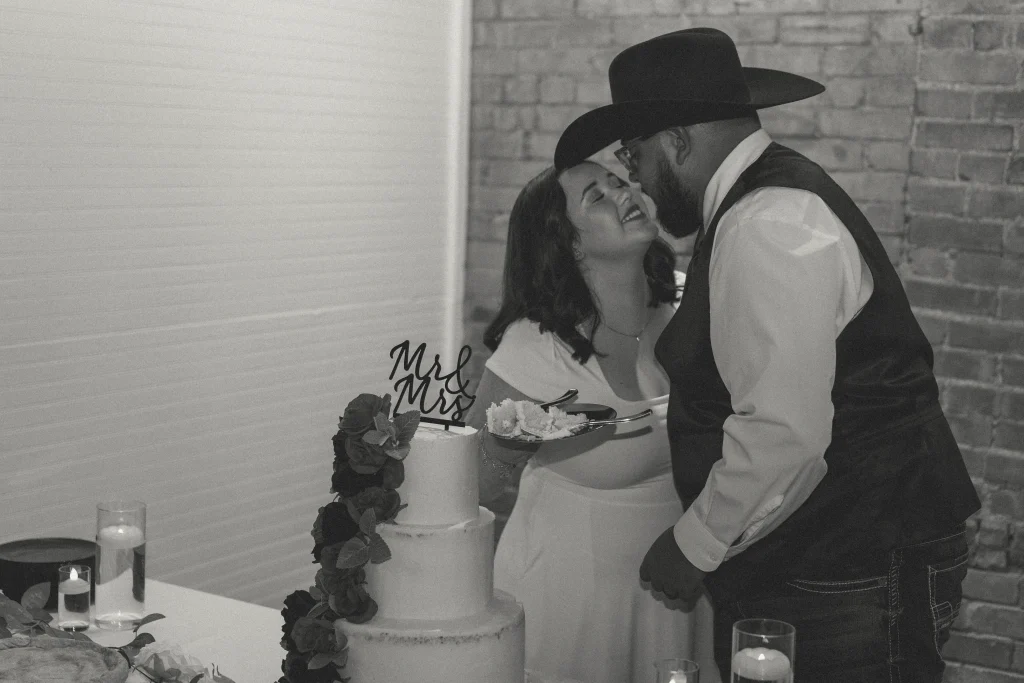 Bride feeding cake to groom as they laugh together during the reception.