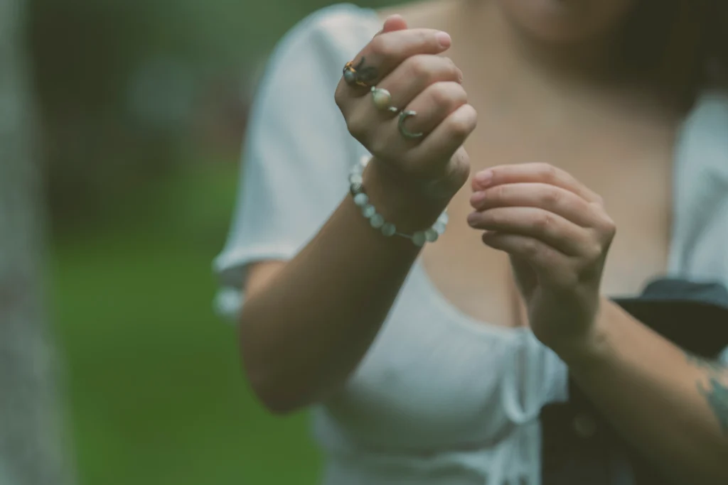 Close-up of a woman’s neck and jewelry, including multiple rings and a dangling earring.