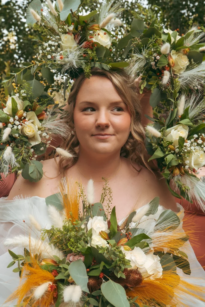 Bride surrounded by bridesmaids’ bouquets, holding her own vibrant fall-colored bouquet for a creative portrait.