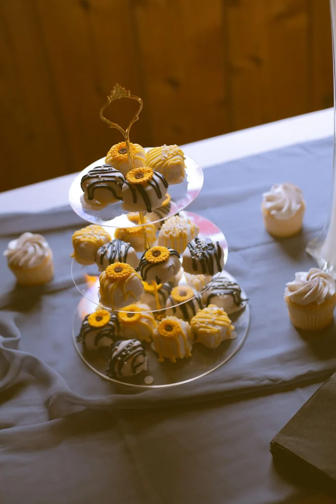 Tiered stand of decorated cake balls in yellow, white, and black with sunflower accents.