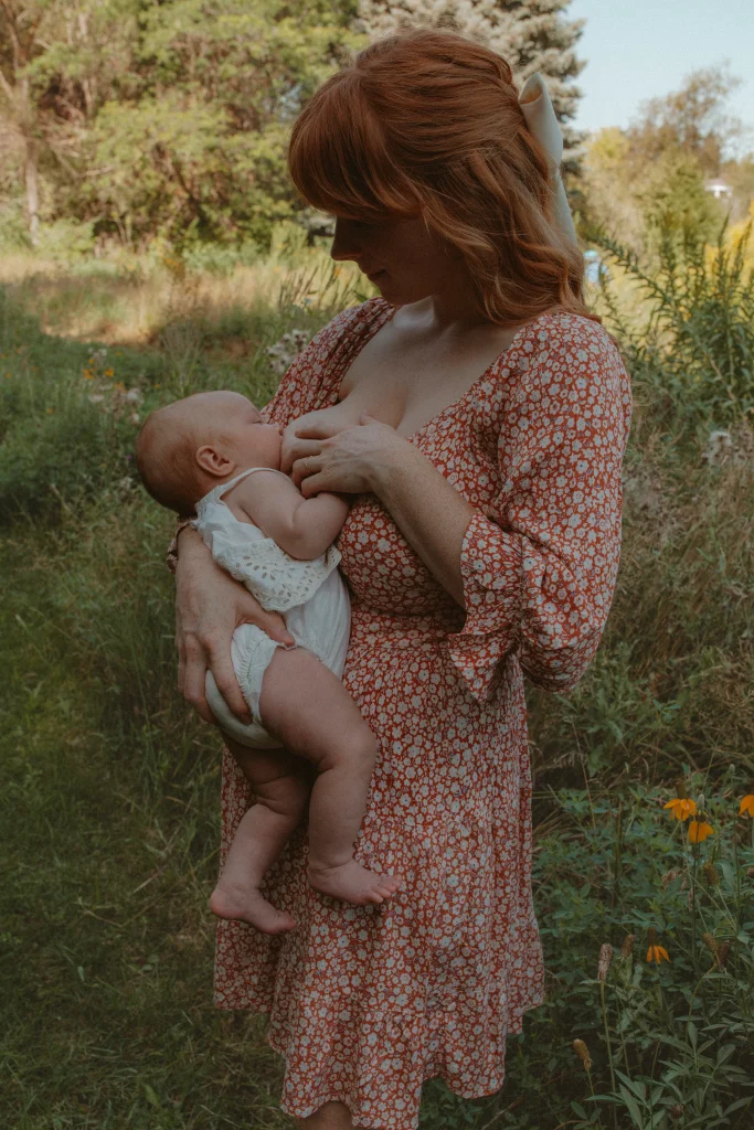 Mother breastfeeding her baby in a meadow.