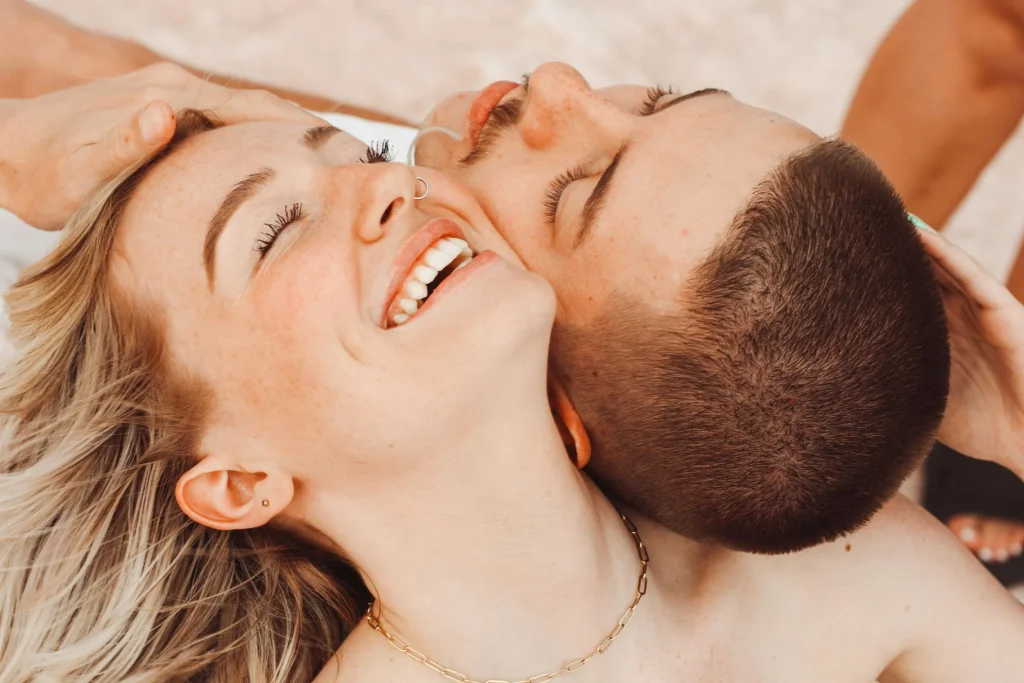 Close-up of couple lying together and smiling, faces touching.